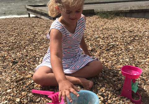 Picture shows young Georgianna playing on the beach with her bucket and spade.
